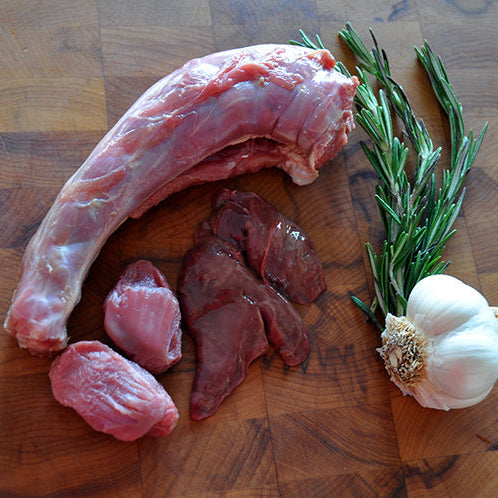 Raw turkey neck and giblets, rosemary sprigs, and a whole garlic bulb arranged on a wooden cutting board.