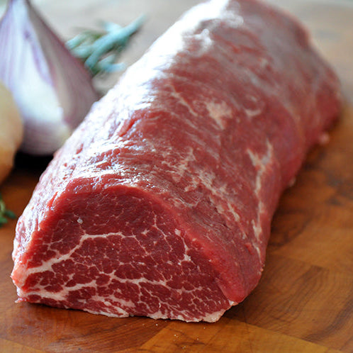 Medium shot of Prime Tenderloin Chateaubriand on a wooden board.