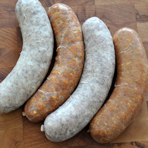 A range of raw sausages on top of a wooden board.