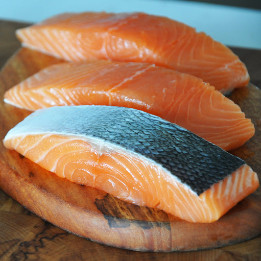 Bright orange Loch Duart Salmon on top of a wooden board
