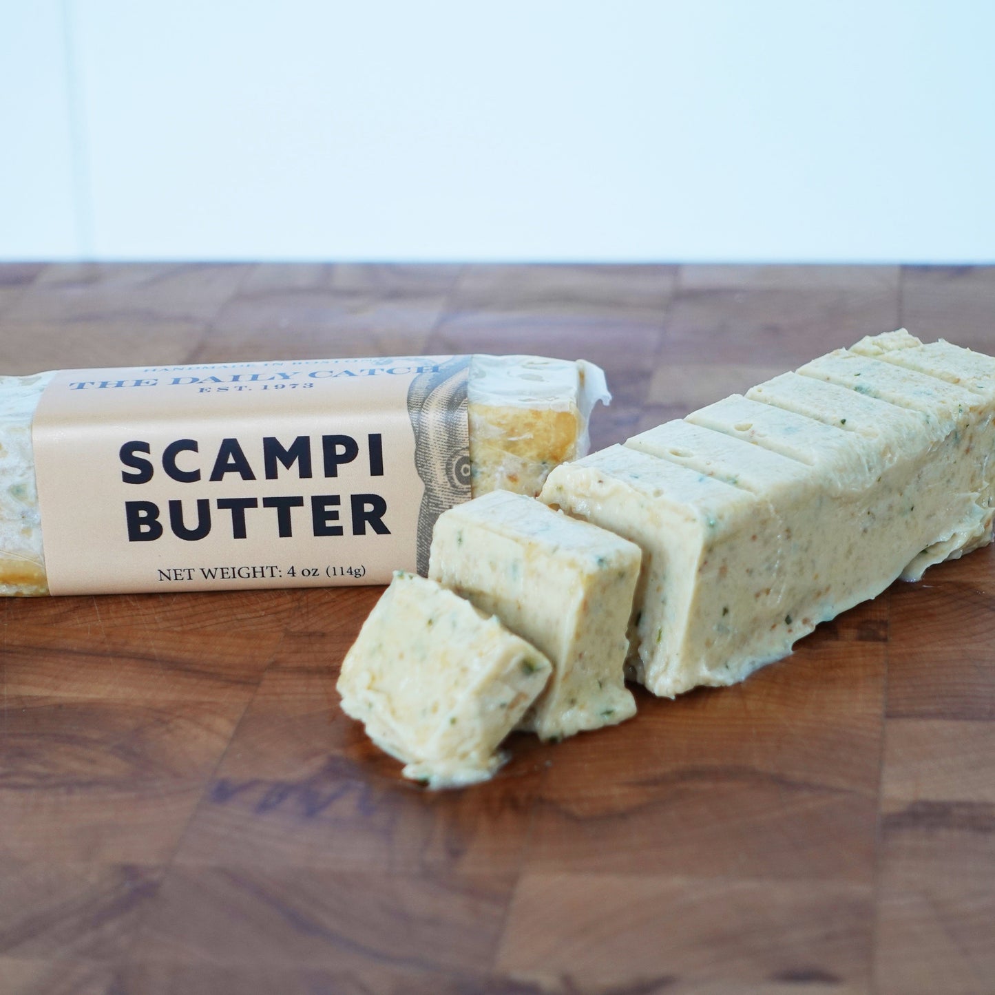 Two butter sticks on a wooden board. The label reads "Scampi Butter"