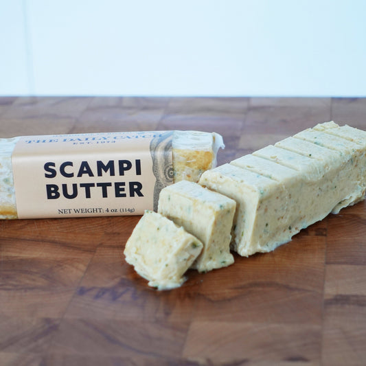 Two butter sticks on a wooden board. The label reads "Scampi Butter"