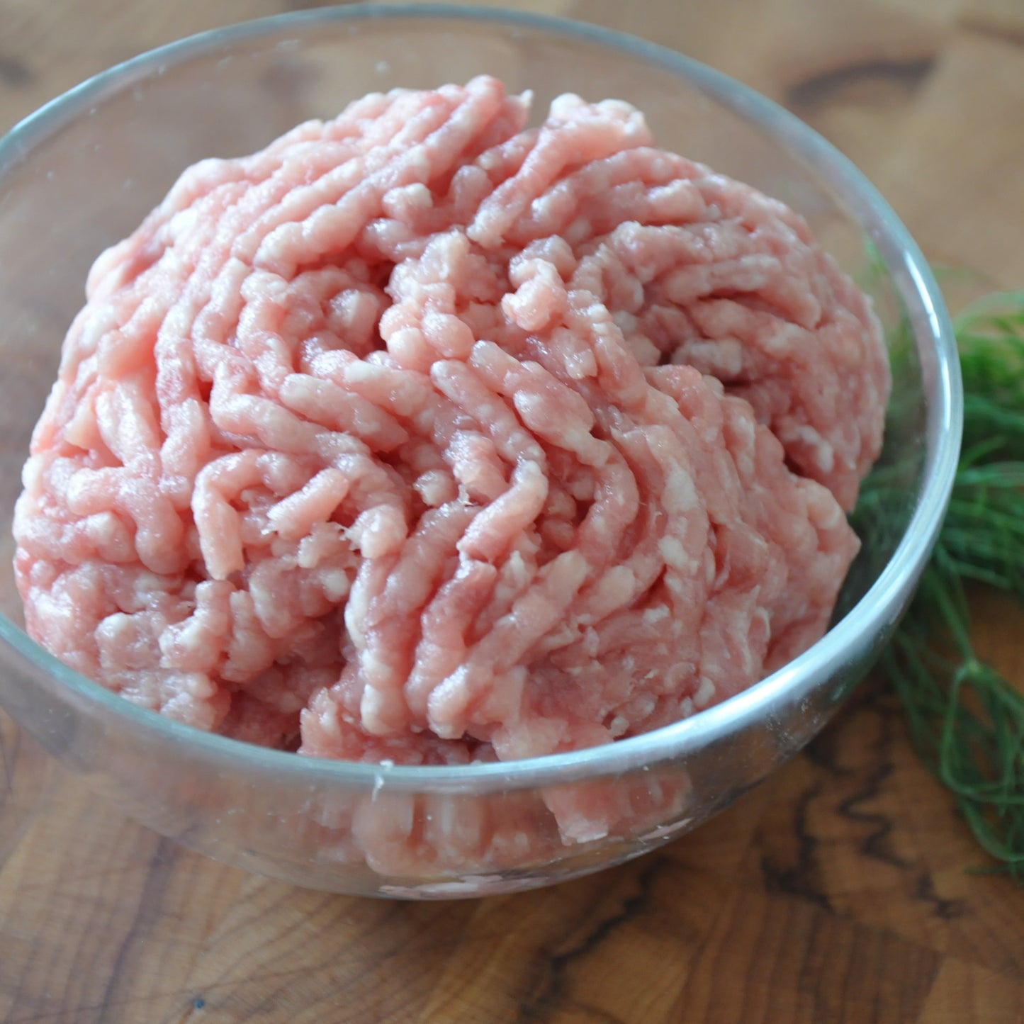 Ground pork in a bowl next to dill