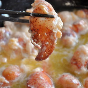 a close up of a lobster meat claw being held by chopsticks. 