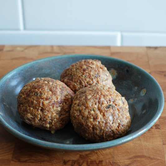 Three raw meatballs in a bowl.